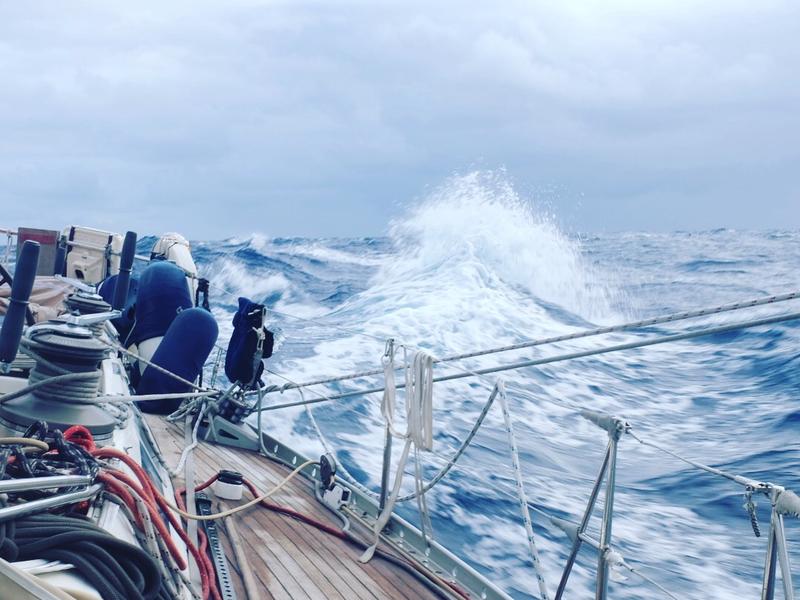 Bow of a sailboat crashing through a breaking wave in heavy weather